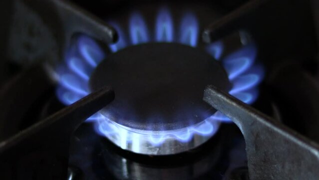 close up gas stoves woman hand turning off or on the blue color flame.4k real time kitchen interior.increasing gas prices,big costs,waste of resources.natural gas flame modern black stove cooking food