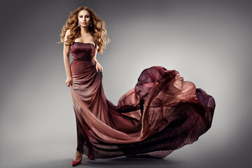 Fashion Model in Black Dress flying on Wind. Beauty Woman with Curly Long Hair in Evening Gown....