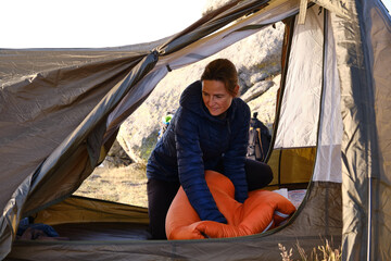 A woman compressing the sleeping bag in the tent.