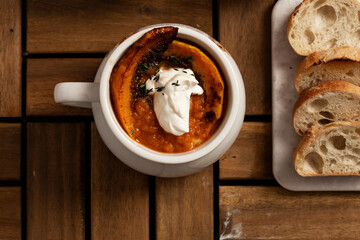 Pumpkin soup in white mug on a wooden table