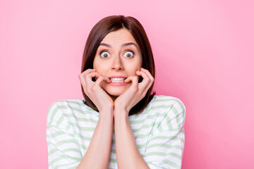 Photo portrait of nice young girl afraid terrible news staring bite nails dressed stylish striped garment isolated on pink color background