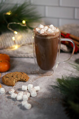 Obraz na płótnie Canvas hot chocolate in a glass mug with mini marshmallows on grey table, blurred xmas background 
