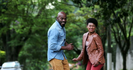 Fototapeta premium Happy carefree black couple dancing together outside in street