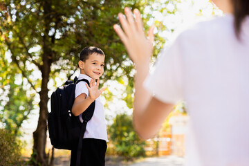 Obraz premium The mother said goodbye to her son, he is going to school in the first grade.