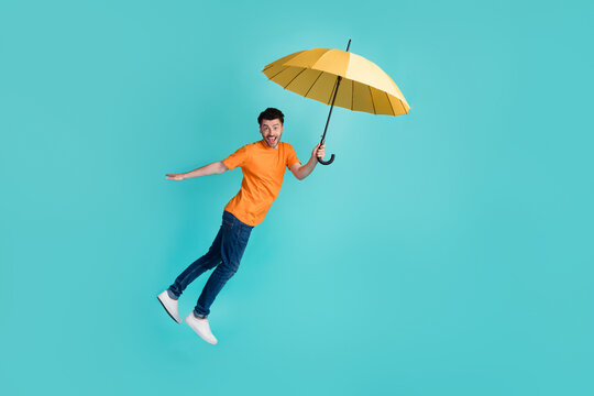 Full length photo of good looking man actor comic animator catch parasol imagine cal fly wind blow isolated on cyan color background