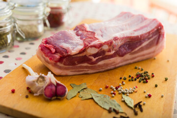 fresh piece of pork belly on wooden board with spices