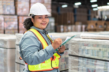 African female manager with checklist document checking stock smiling to camera in the warehouse...