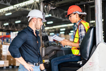 Male factory foreman holding document discuss and explain work project to female worker on forklift in the industry warehouse. Logistic shipping delivery career. © winnievinzence