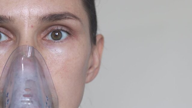 close up woman eyes nose half face uses inhaler nebulizer.female girl treat respiratory virus diseases.breathing through silicone mask sexy vision eyes look ahead.salted solution,sodium chloride,steam