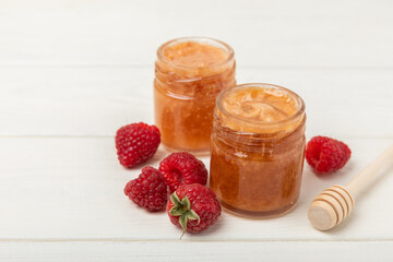 Jar of honey with raspberries on a white wood. Cold medicine. Useful fortified jam for health and beauty. Cream honey. Vegetarian diet organic product. Copy space. place for text