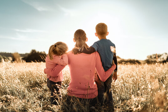 motherhood, and family parenting concept. mother and children spending time together in nature field looking out to the sunset view.	