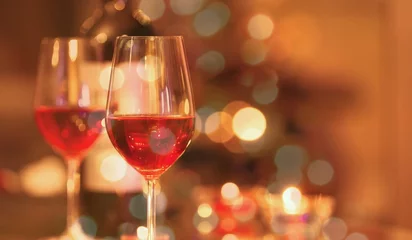 Foto op Plexiglas Twee glazen rode wijn en kerstverlichting achtergrond. © kieferpix