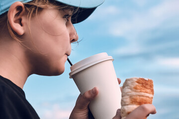 Cute teenage girl drinks cocoa and eats croissants, close-up. Beautiful child 10 -12 years old has...