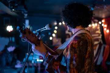 A young Mexican musician is singing and playing jarana guitar during a live concert