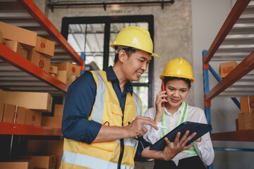 Two Asian warehouse workers check and count inventory accurately and tidy with their tablet computer.