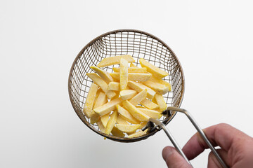 raw fries in a fryer sieve, making French fries