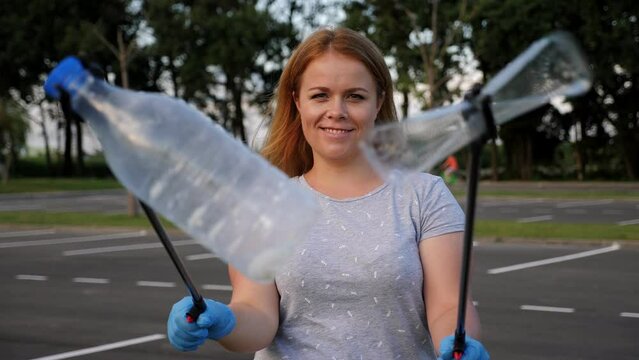 Portrait of a female volunteer with tongs for collecting plastic garbage in her hands. The concept of volunteering and garbage collection. Environmental protection.
