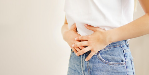 Woman suffering from stomach ache. Holding belly and feeling abdominal menstrual pain or bowel and digestion problems	