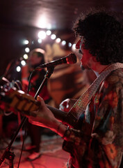 A young Mexican musician is singing and playing jarana guitar during a live concert