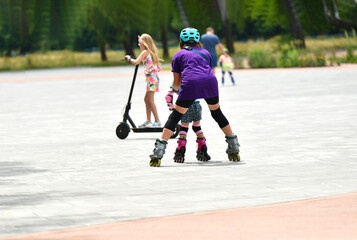 Young mother and her little daughter rollerskating in summer park. happy family have fun. High quality photo - obrazy, fototapety, plakaty