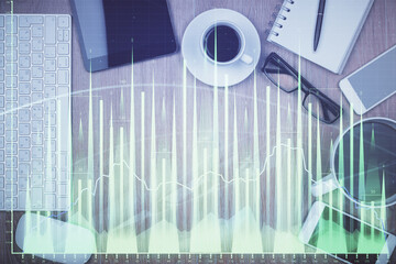 Double exposure of financial chart hologram over desktop with phone. Top view. Mobile trade...