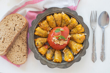 Stuffed zucchini flowers around stuffed tomatoes in the middle on a metal plate