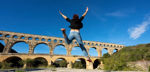 Papier Peint photo autocollant Pont du Gard View of Woman jumping in front of Pont du Gard