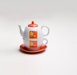 Christmas themed ceramic teapot, on top of a cup, with a santa claus illustration, isolated on white