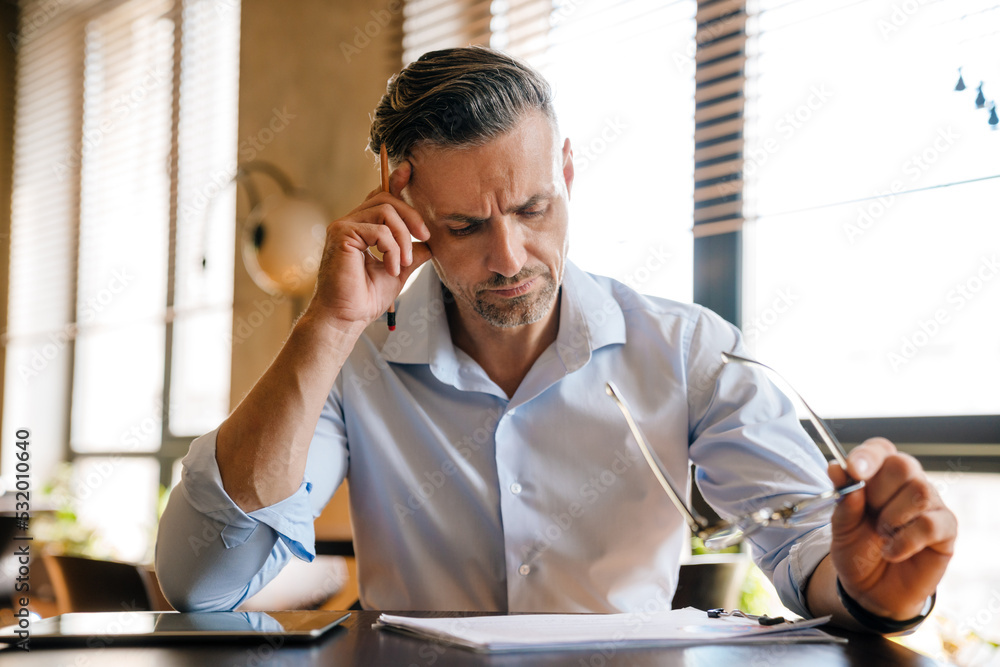 Wall mural european grey man working with papers while sitting at desk in office