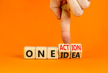 One idea and action symbol. Concept words One idea and One action on wooden cubes. Businessman hand. Beautiful orange table orange background. Business One idea and action concept. Copy space.