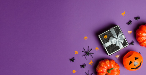Halloween gifts and sale. Black gift box and traditional halloween decorations on purple...