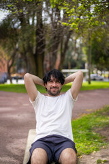 Portrait of handsome attractive mature bearded athletic latin man guy 40s doing sit-ups in the park.