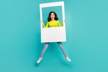 Full size portrait of excited cheerful girl jumping arms hold paper album set card isolated on...