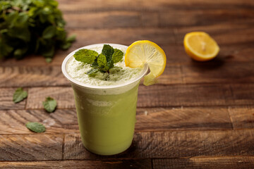 Lemon mint juice with lime slice and mint leaves served in glass side view on wooden table morning meal