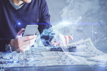 Double exposure of man's hands holding and using a digital device and tech theme hologram drawing....
