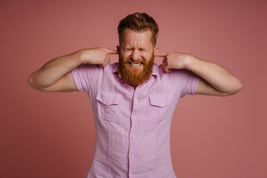 Ginger Displeased Man Grimacing While Plugging His Ears