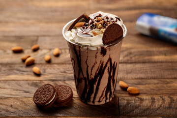 Oreo milkshake with oreo biscuits, almond served in glass side view on wooden table morning meal