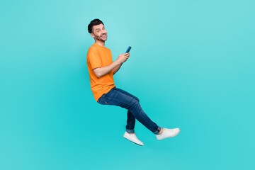 Profile side full body photo of positive guy sit invisible chair blogging device isolated on cyan color background