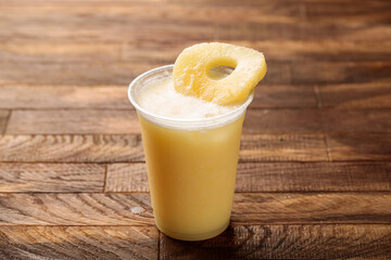 Fresh pineapple juice with pineapple slice served in glass side view on wooden table morning meal