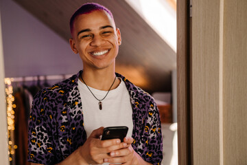 Portrait of young handsome stylish smiling boy holding phone