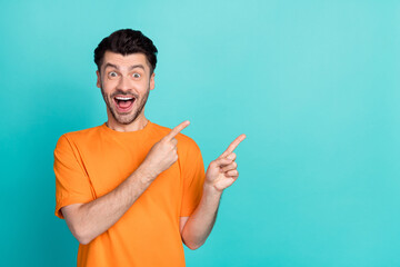 Fototapeta premium Photo of young handsome funny amazed positive man student wear orange t-shirt fingers pointing empty space excited isolated on aquamarine color background
