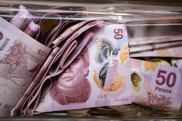 La alcancía de vidrio está llena con billetes de 50 pesos mexicanos.
