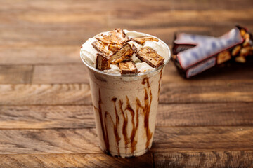 Snickers milkshake served in glass side view on wooden table morning meal