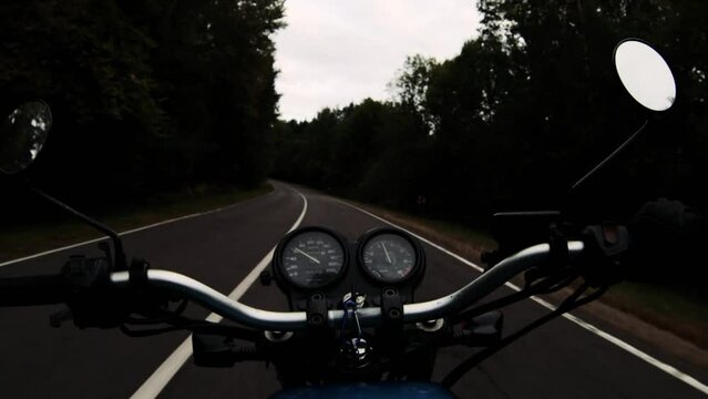 retro motorcycle on an asphalt forest road on a cloudy day in autumn. Dramatic trip.	
