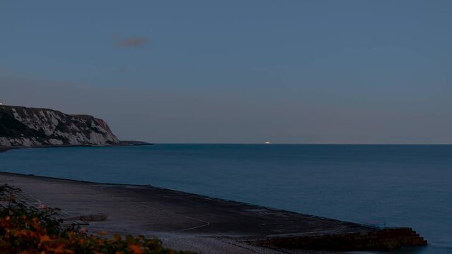 Time lapse shot of the cliffs at Weams Bay at dusk with colorful clouds and the wide ocean