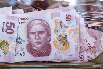 Muchos billetes de 50 pesos mexicanos están en la alcancía de cristal.
