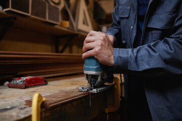 Closeup male worker cutting wood in workshop with electric tool, copy space