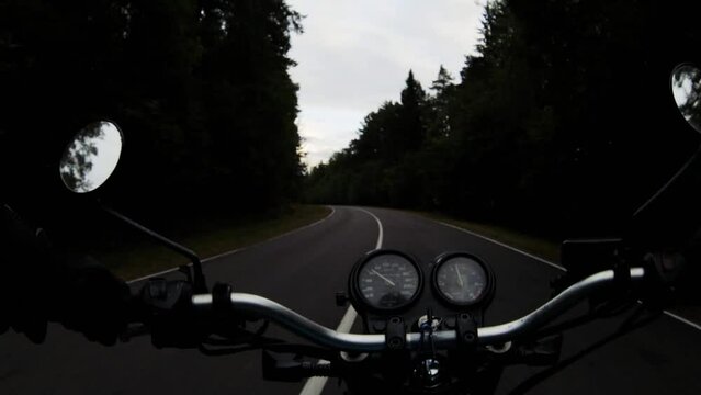 riding a motorcycle from the point of view of a motorcyclist, riding a winding forest road. Noise in video.