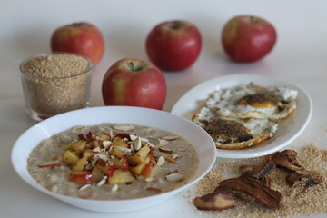 Healthy breakfast combination. Broken wheat porridge and fried egg. Porridge topped with cinnamon flavored caramalised apples and sliced almonds
