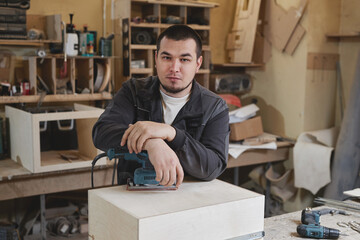 Fototapeta premium Portrait of confident male worker looking at camera while standing in woodworking workshop, copy space